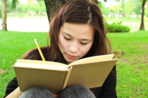 Young woman outdoors writing in a book