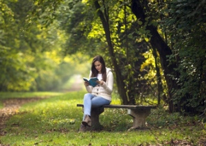 woman reading a book on a park bench